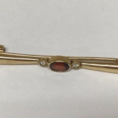 A 9carat gold bar brooch set with a garnet flanked by small diamonds.weight 2.8g