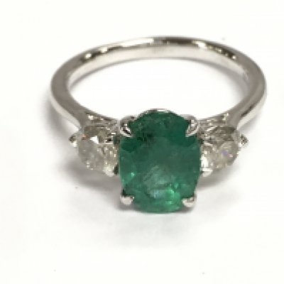 A platinum trilogy ring set with central oval emerald flanked by two diamonds. Emerald 1.94ct and diamonds 0.73ct approximately. Size N