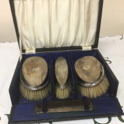 A cased set of three silver mounted brushes with a comb in a fitted case.