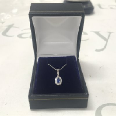 9ct white gold oval sapphire and RBC diamond cluster pendant on a 9ct white gold chain, boxed. Sapphire 0.39ct. Diamonds 0.07ct.