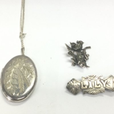 A silver locket on silver chain along with two silver brooches. 23.18g Postage A