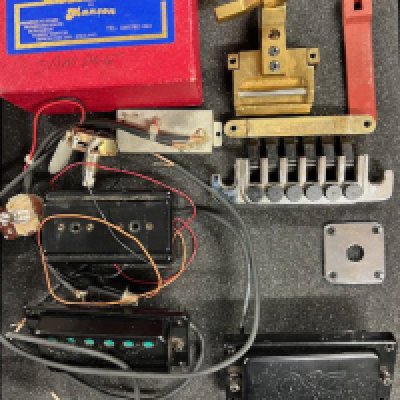 A miscellaneous selection of guitar parts useful for a repairer or hobby guitarist. A Manson Slideslammer in brass with retainer protector, box and paperwork. A Gibson TP6 adjustable tailpiece in chrome, a Gibson ABR1 bridge plate in gold with no saddle. Two early 1980's OSC Active pickups. A Gibson jack plate in chrome. A Bass Guitar pickup with bakelite possibly Gibson.