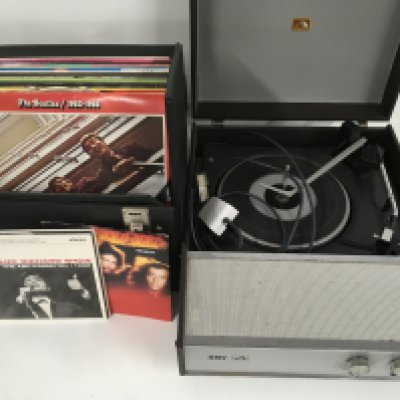 An HMV portable record player and a record case of LPs and 7" singles by various artists including The Beatles, Elvis Presley and rock n roll compilations.