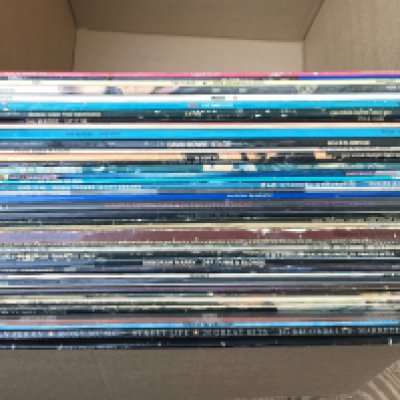 A box of LPs by various artists including PiL, The Beatles, David Bowie and others.