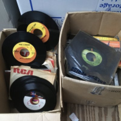 Three boxes of 7" singles and cassettes by various artists including some US and Canadian pressings.