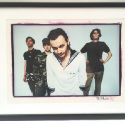 A framed and glazed limited edition Mitch Ikeda print of The Manic Street Preachers, signed by Mitch and with COA to the reverse signed by James, Nicky and Sean. Approx 62cm x 48cm.