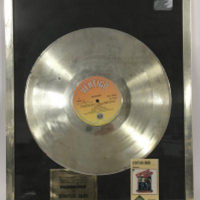 A framed and glazed silver disc commemorating sales of the Status Quo album 'Piledriver', approx 37.5cm x 48.5cm.