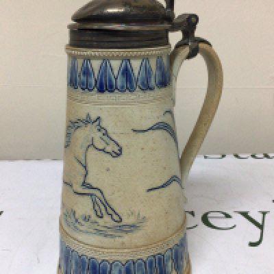 A Lambeth Doulton Victorian stoneware jug with a silver hinged top the sides with horses and a repeat pattern boarder. damage to the handle Hight 26cm marks to the base. NO RESERVE