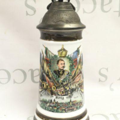 A German decorated stein with emblems of militaria and empower, the metal lid decorated with small cannon and eagle. 27cm tall. This lot cannot be posted