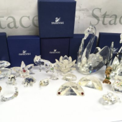 A collection of Swarovski crystal glass figures including Shell with pearl, Orchard pink, Wolf, Artic fox, water lily, Treasure chest etc. some boxed and also Julien Macdonald swan figures. This lot cannot be posted