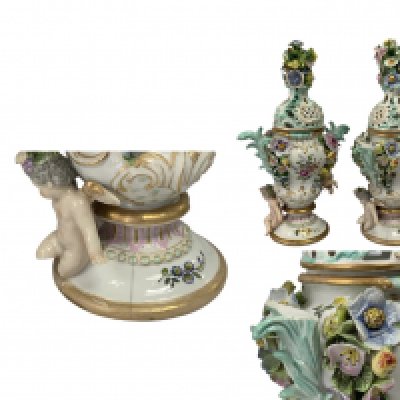 A pair of 19th Century German porcelain pot pourri vases and covers with cherub and floral decoration. 36cm. (Some areas of damage).