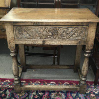 A carved oak side table with a single drawer . Dimensions 42cm deep 78cm wide 78cm tall.