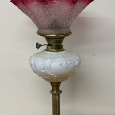 A Victorian brass footed oil lamp with cranberry etched shade.