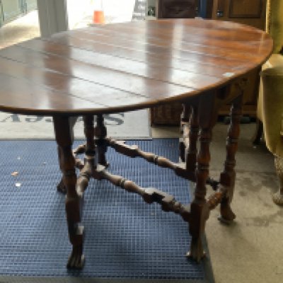 A carved hardwood oval drop leaf dining table with plank top. 143cm x 91cm x 77cm