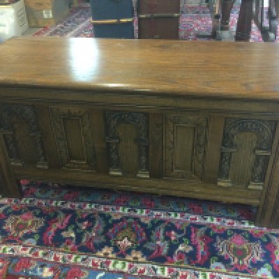 A oak blanket box with carved panel front .