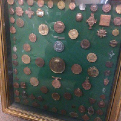 A case containing military medals, badges, coins and tokens . This lot cannot be posted