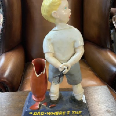 Advertising shop display figure, "DAD- WHERE'S THE DUROFIX", depicting a young boy with his arms behind his back holding a catapult and with a broken vase to his left, 24.5cm wide, 38cm high