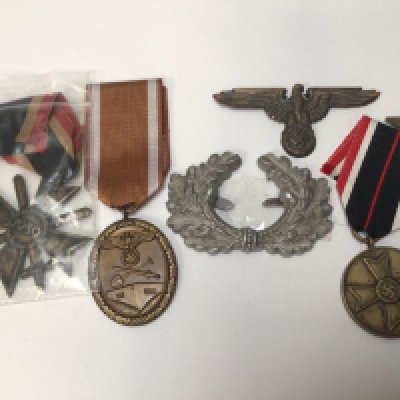 A collection of German Third Reich II world war medals and badges a Civilian war merit medal A West Wall medal A second class war merit medal and two other badges.
