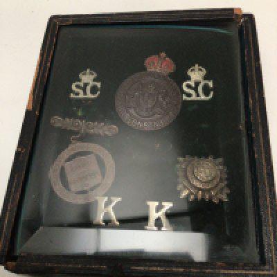 A damaged leather and glass case containing early 20th century Metropolitan Police badges possible Kings Coronation body Guard