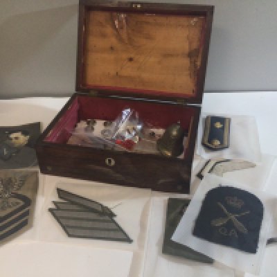 A Rosewood box containing Military cloth badges British and American other badges and a small helmet shaped bell.