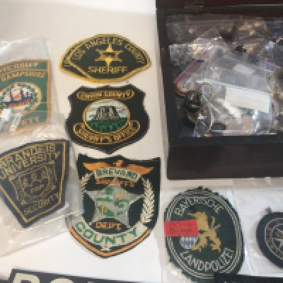 A Mahogany box containing American Police County cloth badges American University Security badges other military police and other associated badges.