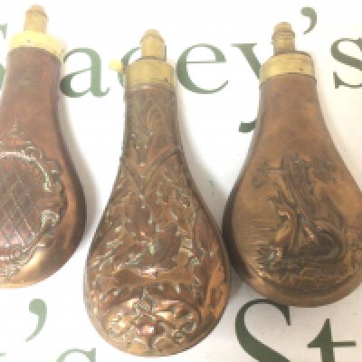 Three 19th Century copper powder flasks. Repousse chased decoration with game birds and brass mounts (3)