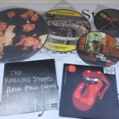 A box of Rolling Stones picture discs, CDs, DVDs and VHS tapes.
