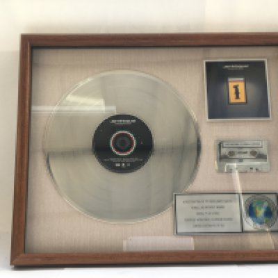 A framed and glazed limited edition platinum disc, CD and cassette display in recognition for worldwide sales of the Travelling Without Moving album by Jamiroquai. Number 5/60. Approx 53cm x 43cm.
