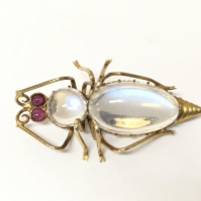 An unmarked yellow metal moonstone and ruby bug brooch.