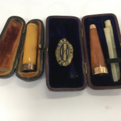 Two amber cigarette holders one marked 9 ct gold .