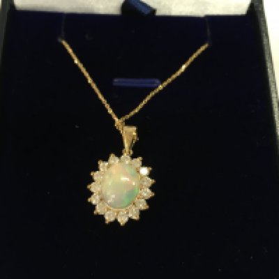9ct yellow gold oval cabochon opal and diamond cluster pendant on a 9ct gold chain. Opal 1.64ct and diamond 0.74ct