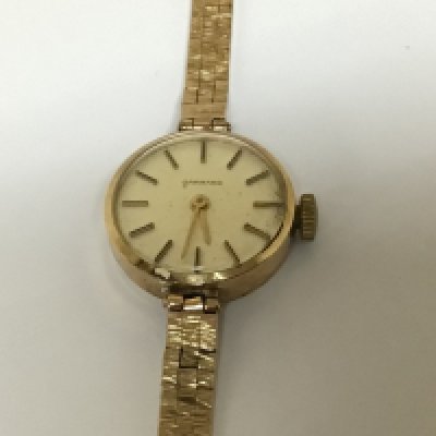 A ladies 9carat gold Garrard Watch with attached 9carat gold bracelet the reverse of the watch with a personal inscription. Weight 17g approximately.