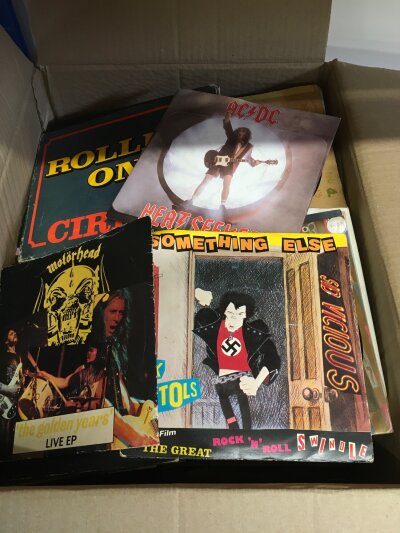 A box of 7" singles by various artists including Sex Pistols, The Jam, The Smiths, The Cure and many more.