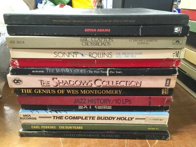 A collection in three large bags of vinyl and cassette box sets by various artists including Bryan Adams, Sonny Rollins, Eric Clapton, Gary Numan and others.
