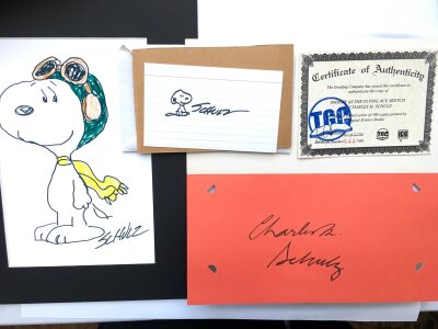 A Snoopy greetings card signed by Charles M Schulz, a small sketch of Snoopy signed by Schulz plus a limited edition print of Snoopy as The Flying Ace with COA.