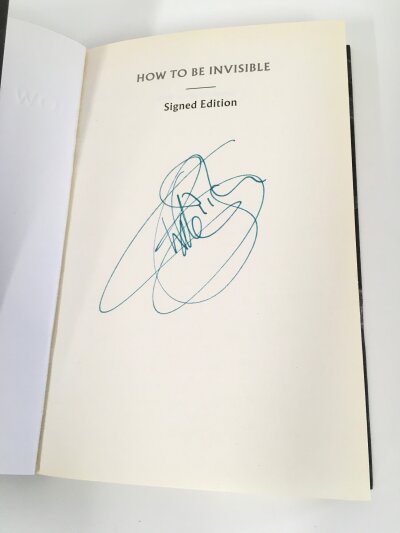 A Kate Bush signed How To Be Invisible paperback book plus a signed fan binder of live show photographs signed by both Kate and her brother Paddy Bush.