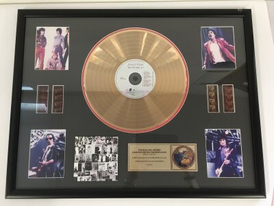 A framed and limited edition Rolling Stones gold disc CD display  with film cels and images of the group, approx 69cm x 54cm.