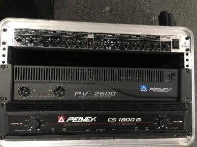 Three rack mounts comprising a Behringer Super X Pro Crossover CX3400, a Peavey PV-2600 power amplifier and a Peavey CS 1800G power amp housed in a hard shell flight case.