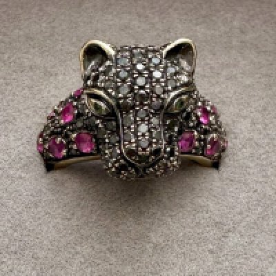A stone set panther head ring stamped 750 set with black diamonds and rubies, Approx weight 6.99 grams. Size L 1/2.