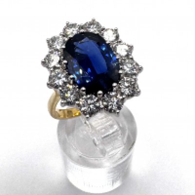 4.80 Carat CAMBODIAN SAPPHIRE AND DIAMOND CLUSTER RING set with an oval cut sapphire of 4.80 carats in a cluster of round brilliant cut diamonds, the diamonds totalling approx 3.30ct F-G colour, VS1-VS2, Fully Hallmarked for 18ct gold, size Q.5, 8.28g. With WGI report. (A)