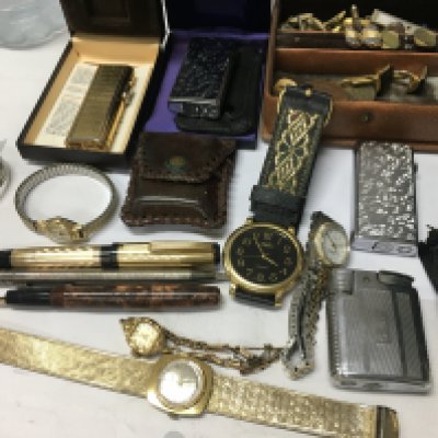 A box containing watches pens and lighters.