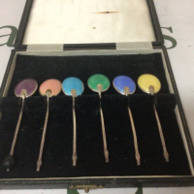 A cased set of silver and enamel coffee spoons.