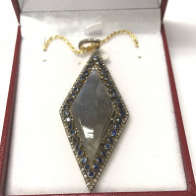 A large rhomboid pendant in yellow metal set with an oval cabochon labradorite surrounded by sapphires and diamonds on a gold plated silver chain. Labradorite 17.33ct sapphires 2.50ct and diamonds 1.25ct approximately.