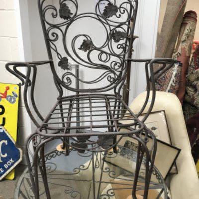 A circular metal garden table with glass top with four chairs