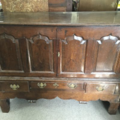 An 18th Century oak cupboard on stand, with a pair of panelled doors with three drawers under