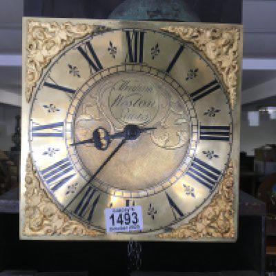 An oak carved 30 hour, brass dial long cased clock. The dial having Roman numerals and 20cm across