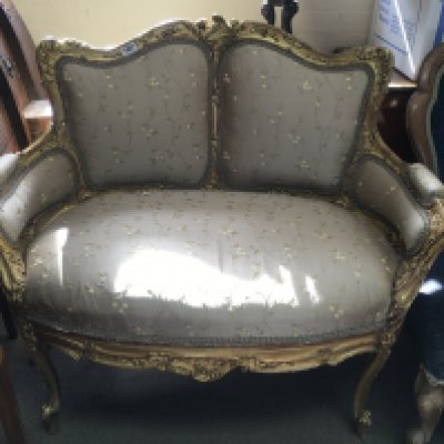 A French Rococo-style love seat. The upholstered back and seat above cabriole legs