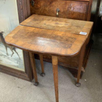 A small walnut veneered occasional table. 48cm x 22cm x 70cm. (In need of restoration).