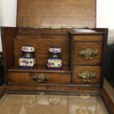 A oak stationary box inset with two inkwells fitted with three drawers.