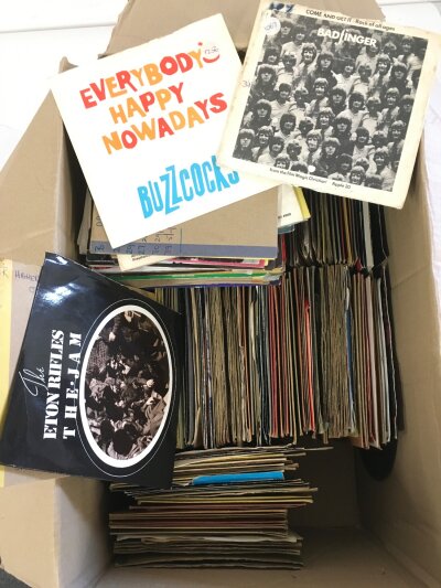 Two boxes of 7" singles by various artists including The Jam, Buzzcocks, Devo and many more.